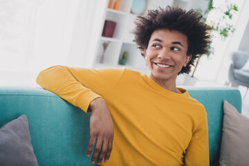 Portrait of nice young man sit chill sofa think wear yellow pullover white interior flat indoors