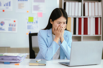Asian businesswoman who is suffering from headache and stress due to overwork.