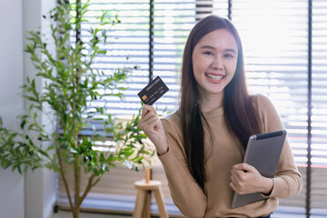 young woman looking at tablet screen holding credit card, using mobile tablet secured online e-banking app, satisfied with online cashback purchase or good electronic banking services.