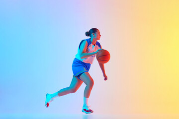 Obraz premium Sportive woman in blue basketball jersey dribbling in motion in neon light against gradient studio background. Concept of professional sport, championship, tournament, hobby and recreation. Ad
