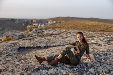 Woman sitting on top of a majestic rock formation with crossed legs in a peaceful meditative pose