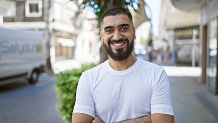 A cheerful young man with a beard stands confidently on a city street, embodying a casual, urban...