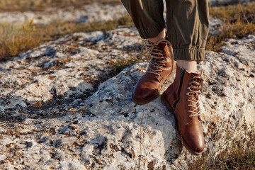 Traveler standing on top of rock in stylish leather combat boots for outdoor adventure and...
