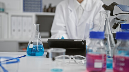 Caucasian woman scientist analyzing data on tablet amidst beakers and microscope in laboratory