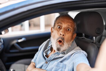 Senior man's amazed face in disbelief, mouth open in surprise as he makes a scared car selfie