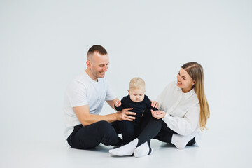 Young happy family couple with baby son on white background. Mom and dad with a baby on a white background.