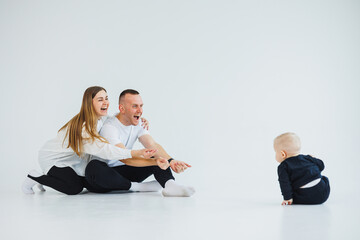 Young happy family couple with baby son on white background. Mom and dad with a baby on a white background.