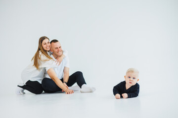 Young happy family couple with baby son on white background. Mom and dad with a baby on a white background.