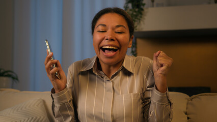 Excited African American woman win online prize in mobile app happy ethnic businesswoman adult...