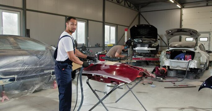Professional mechanics using tools and equipment to repair and renew car parts at an automotive repair service station. Grinding machine. Grinding the car before painting. Repair after an accident.