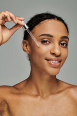 Young African American woman in strapless top applying serum