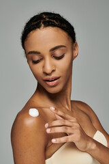 A beautiful young African American woman in a strapless top applying a thick layer of cream to her...