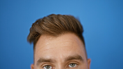 Close-up portrait of a young hispanic man with a stylish haircut against a blue outdoor background.