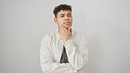 Handsome young man with beard in thoughtful pose against white wall, evoking introspection and style.