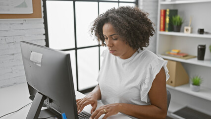 African american woman with braids working at computer in office - Powered by Adobe