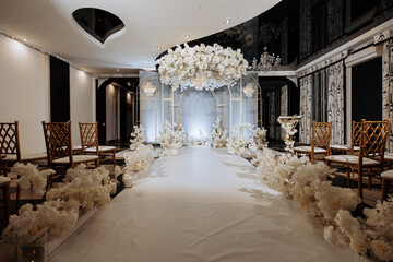 A long white carpeted hallway with a white archway and white flowers