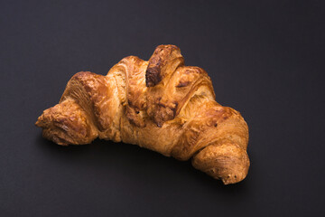 Fresh croissant on a black slate background.