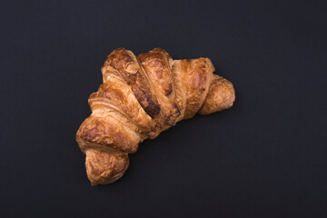 Fresh croissant on a black slate background.
