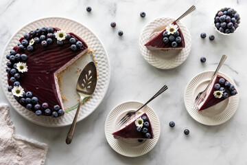 A blueberry cheesecake with serving slices to the side, ready for eating.