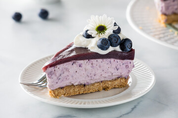 A serving slice of creamy delicious blueberry cheesecake, ready for eating.