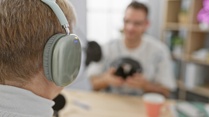 A woman with headphones interviews a blurred man on a podcast in a studio, creating a dynamic...