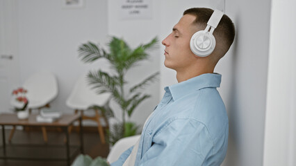 Hispanic man relaxing with headphones in a modern lobby interior