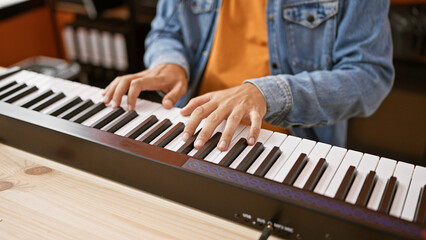 Hispanic man playing piano indoors at a music studio, showcasing his musical talent in a casual setting.