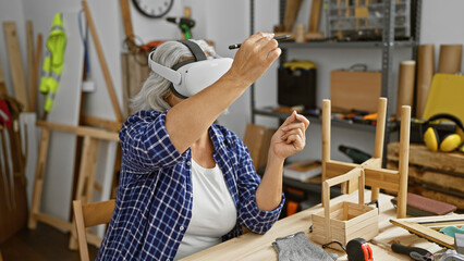 Grey-haired woman using virtual reality headset in carpentry workshop