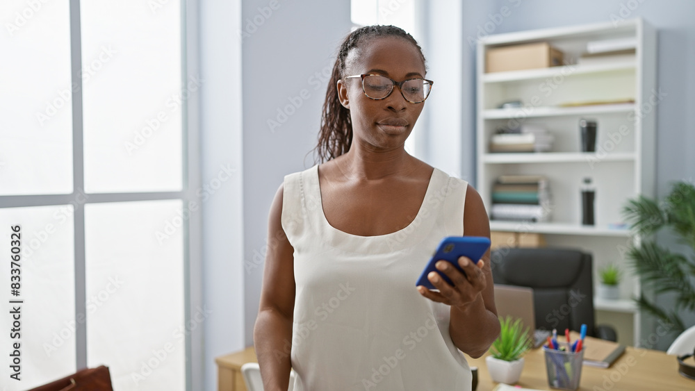 Wall mural Professional african woman using smartphone in modern office interior