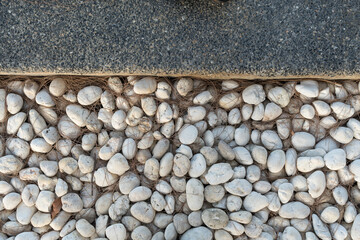Close up of white pebbles stone and gray cement stone decorative fern in a garden