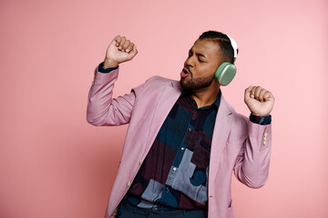 young African American man wearing a pink jacket and listening to music on headphones.