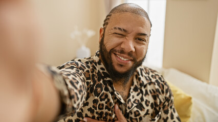 Handsome african american man with a beard smiling for a selfie in a stylish bedroom