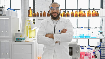 Confident man in lab coat standing with arms crossed in a modern laboratory, exuding...