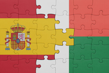 puzzle with the colourful national flag of madagascar and flag of spain.