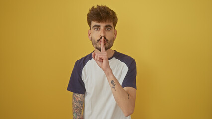 Hispanic man with beard gesturing silence against yellow background