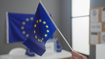 Young man holds a european union flag in a room with ballot boxes, symbolizing democracy and voting...