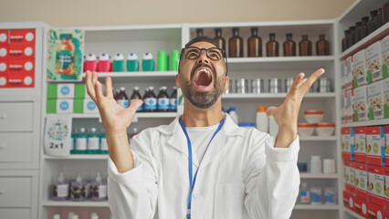A young hispanic male pharmacist expresses frustration in a well-stocked drugstore interior.