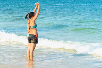 Mother and teenage daughter playing together on tropical beach at daytime. Mom and lovely daughter enjoy and fun outdoor lifestyle on beach. Happy family outdoors vacation. Friendly family Concept.