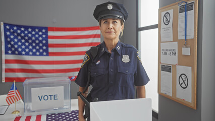 A mature policewoman stands indoors near an american flag at a voting station, symbolizing...