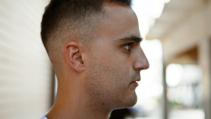 Obraz premium Close-up of a handsome young man outdoors, with city street in a blurred background, evoking an urban lifestyle vibe.