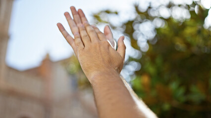 Close-up of man's extended hand in a natural park with blurred greenery in the background portraying connection with nature.