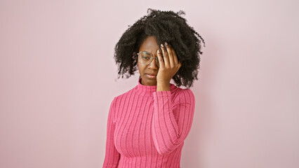 African american woman in pink feeling stressed indoors with hand on face.