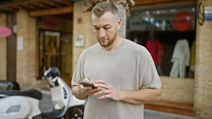 Handsome caucasian male with a beard using smartphone on urban street