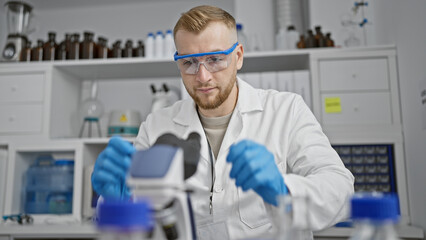 A focused young man in lab coat conducts experiments in a modern laboratory setting.