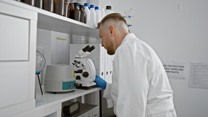 A focused caucasian man with a beard works meticulously in a laboratory setting.