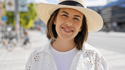 Beautiful young hispanic woman smiling confident wearing summer hat in the streets of Stockholm