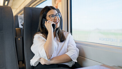 Young beautiful hispanic woman smiling speaking on the phone sitting inside train wagon