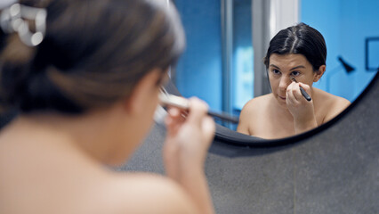 Young beautiful hispanic woman applying make up in the bathroom