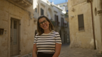 A young, hispanic, beautiful woman smiling in the historic streets of lecce, a charming town in puglia, italy, bathed in warm sunlight.