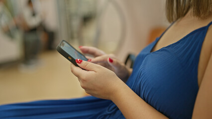 Chatting and clicking away, young woman uses smartphone while sitting inside an empty subway car, a...
